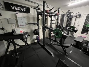 Ett välutrustat hemmagym med powerrack och viktskivor i ett kompakt utrymme.