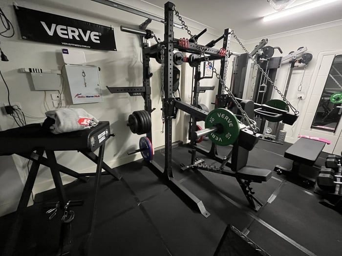Ett välutrustat hemmagym med powerrack och viktskivor i ett kompakt utrymme.